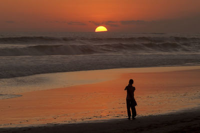 Full length of man walking on beach during sunset