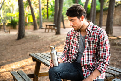 Thoughtful young man sitting on bench in park