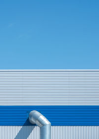 Minimal photograph of a blue warehouse with  shadow and blue skies 