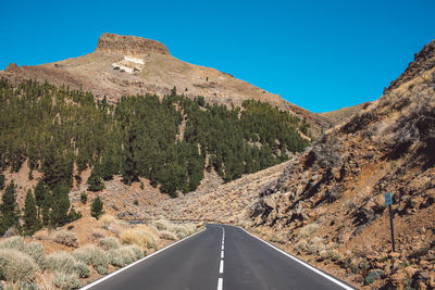 Road amidst mountains against clear blue sky