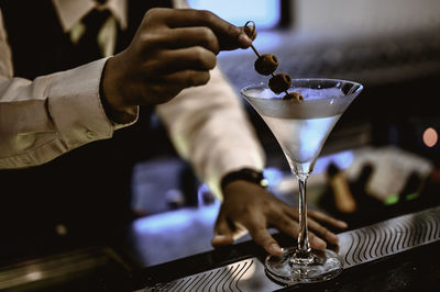 Midsection of bartender preparing drink at counter