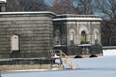 Building by frozen central park reservoir during winter