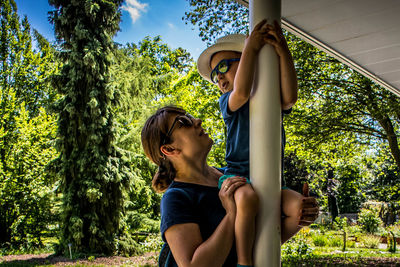 Side view of mother and daughter against trees