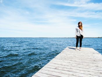 Woman standing by sea against sky