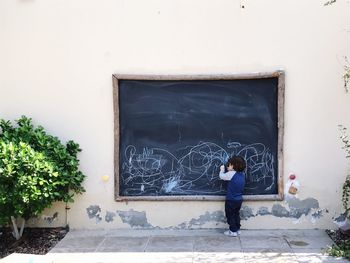 Full length of boy drawing on blackboard