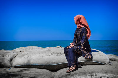 Woman in sea against blue sky
