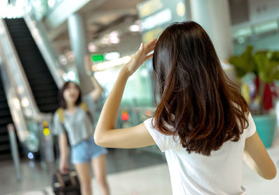 Rear view of woman with arms raised standing in corridor