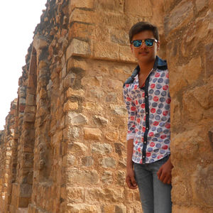 Man wearing sunglasses standing against wall