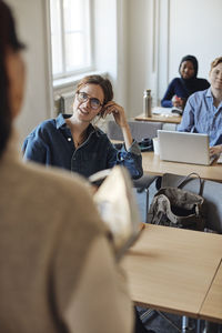 Female student talking to teacher during lecture in classroom