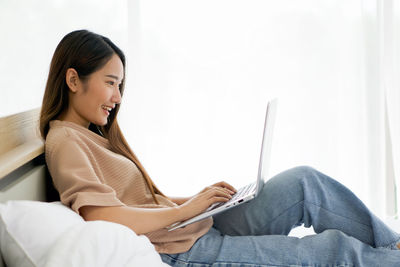 Young woman using phone while sitting on sofa