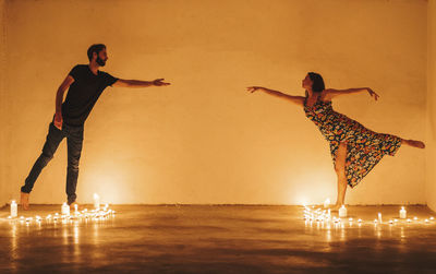 Digital composite image of people standing by illuminated building against orange sky