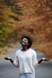 Young woman looking away while standing on autumn leaf