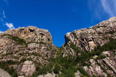 Low angle view of rocky mountains against clear blue sky