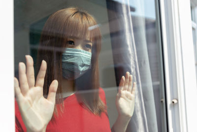 Portrait of woman holding glass window