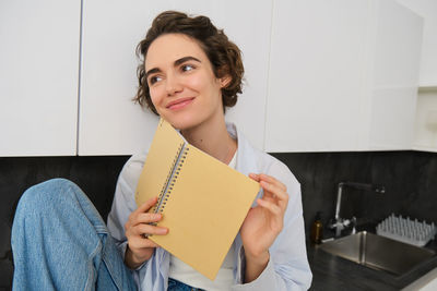 Portrait of young woman using digital tablet while sitting on table