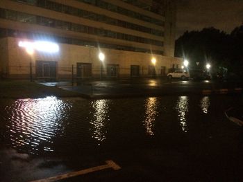 Reflection of illuminated buildings in puddle at night