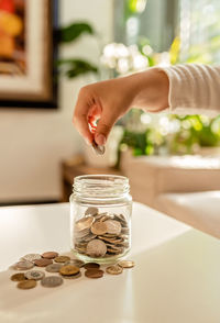 Hand of little child putting coin into glass jar. kid counting money saving from change learn save