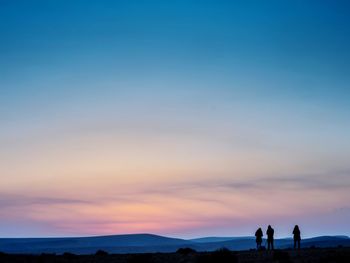 Silhouette people standing on mountain against sky during sunset