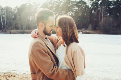 Smiling young couple romancing at riverbank