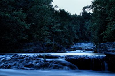 Scenic view of waterfall in forest against clear sky