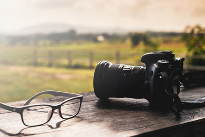 Close-up of camera and eyeglasses by field on table