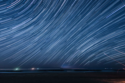 Light trails on sea against sky at night