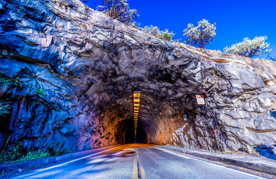 Road amidst trees against blue sky