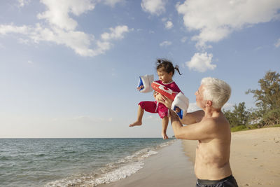 Grandfather playing with granddaughter on beach
