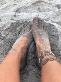 Low section of woman standing on sand