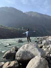 Full length of man standing on rocks against mountain