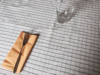 Empty glass with fork and napkin on tablecloth