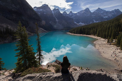 Rear view of woman looking at lake against mountains