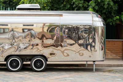 Retro style futuristic silver metal trailer van standing on summer day for fair, festival or event.