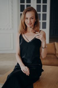 Portrait of young woman sitting on sofa at home