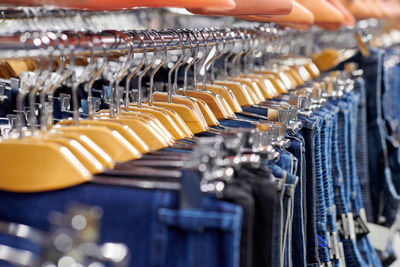 Row of hanged blue and black jeans on wooden hangers in shop. many jeans hanging on rack