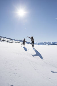 Young woman with her dog playing on snow land