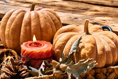 Cozy warm autumn composition with burning candle and pumpkins on knitted woolen plaid.