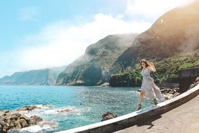 Woman standing by sea against sky