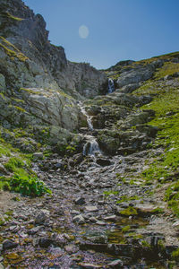 Scenic view of stream amidst rocks against sky