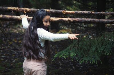 Side view of girl standing against trees