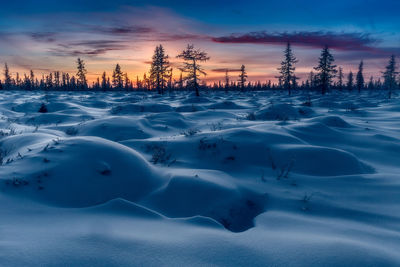 Scenic view of snow covered landscape against sky at sunset