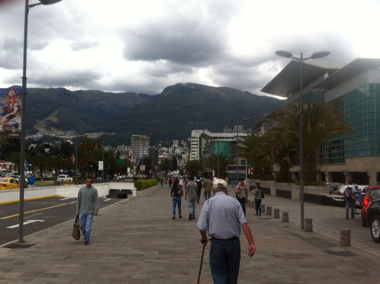 building exterior, architecture, built structure, sky, men, walking, person, mountain, street, lifestyles, city, cloud - sky, large group of people, city life, leisure activity, road, cloud, rear view, the way forward