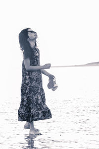 Side view of girl standing at beach against clear sky