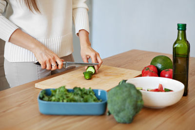 Close up woman's hands preparing vegan salad with fresh vegetables. model cutting with knife salad