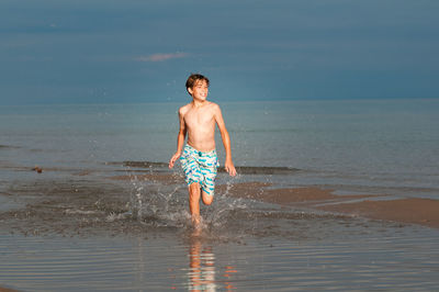 Front view of boy running in sea