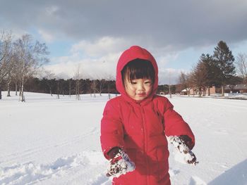 Smiling girl standing in snow against sky
