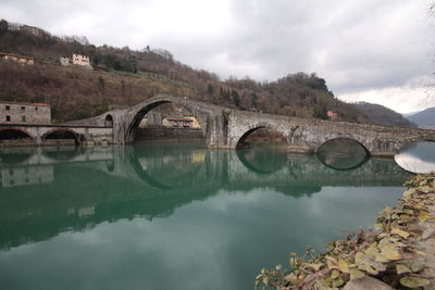 Arch bridge over river against sky