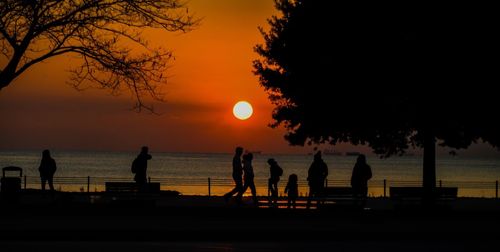 Silhouette people standing at beach during sunset