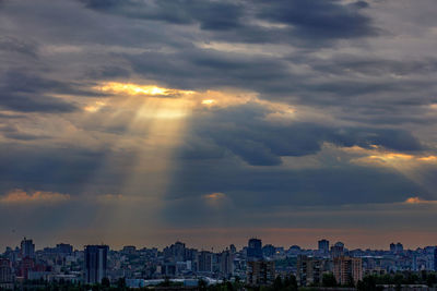 The sun's rays break through dense clouds at dawn over a sleeping city. shining light in the sky.