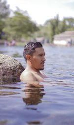 Portrait of shirtless man swimming in lake